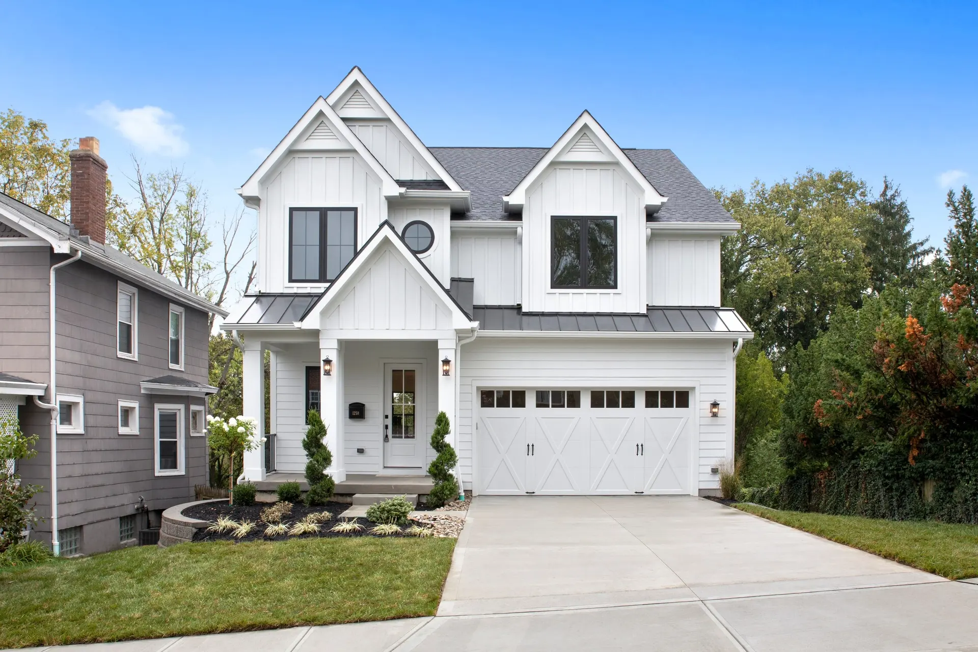 1258 Morten Ave. in Hyde Park: a white modern farmhouse with board-and-batten gables, black windows, a small front porch and a white two-car garage
